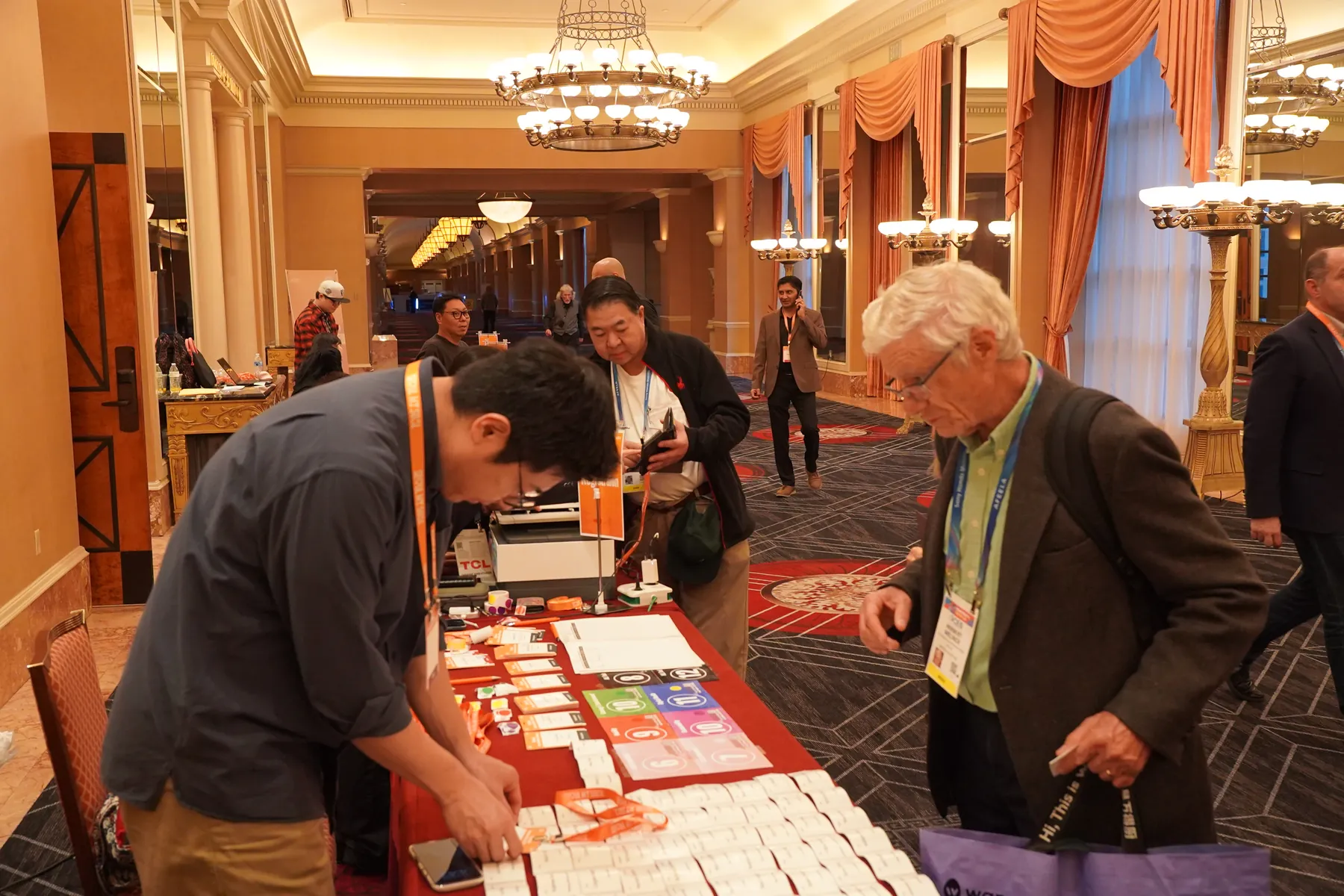 Attendees browse badges and materials under the ballroom chandeliers