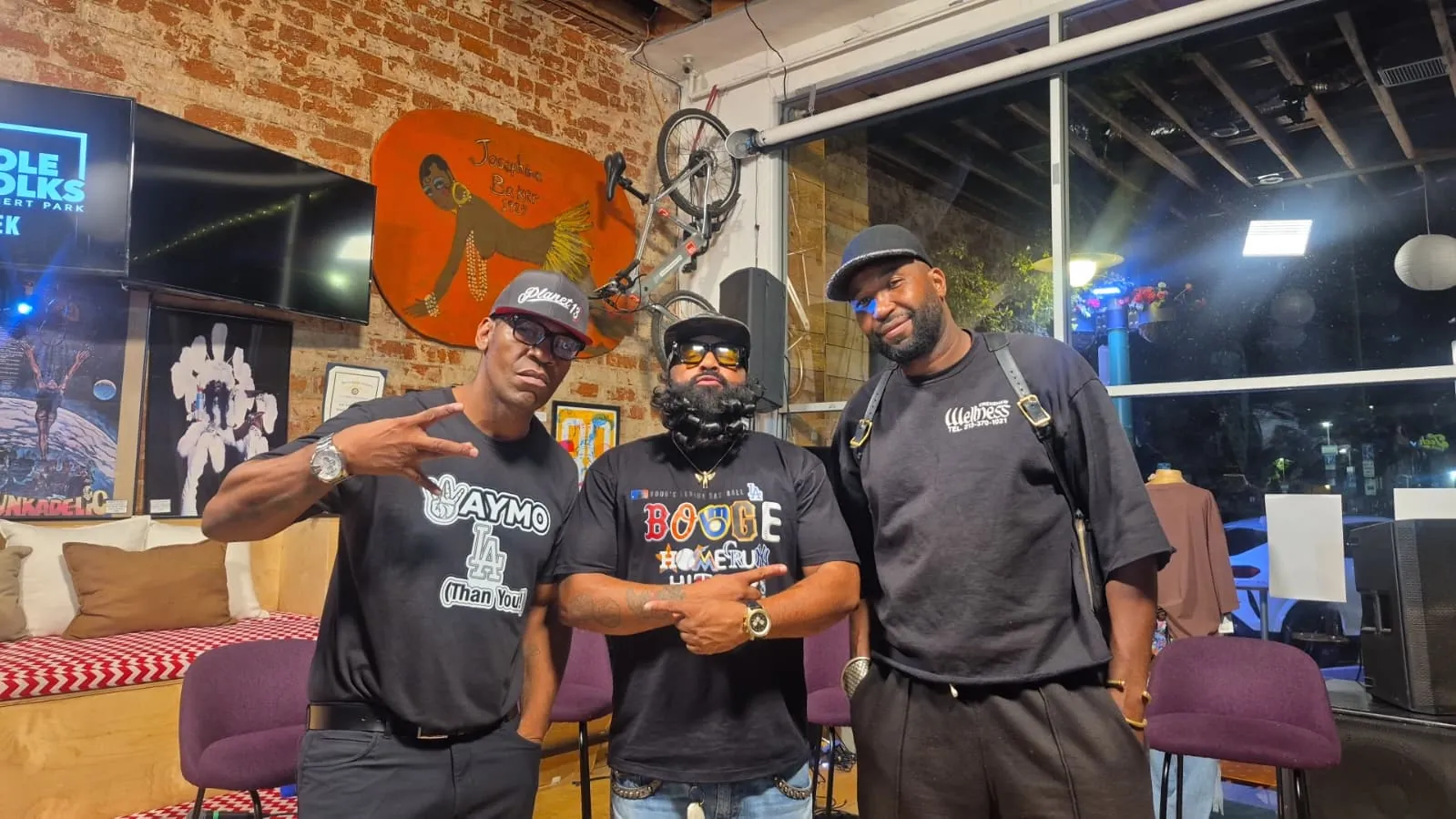 Three guests pose by the mural and bike wall